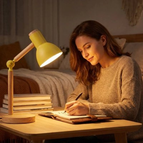 Femme dans chambre en train d écrire éclairée par Lampe de bureau jaune sur la table