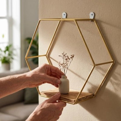 Une main pose un pot de fleur sur Petite etagere mural doré au mur 