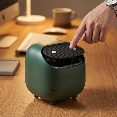 Doigt appuie sur couvercle de Poubelle de bureau vert dans un bureau