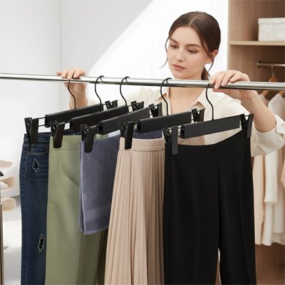 Femme accroche pantalon sur Cintre pantalon​ dans chambre