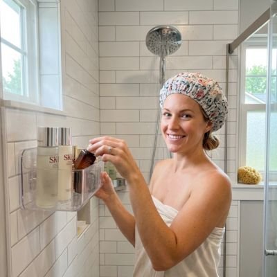 Femme souriante en serviette prendre gel douche dans Etagere douche pour bain