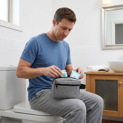 Homme assis sur toilette range affaires dans trousse de toilette homme gris