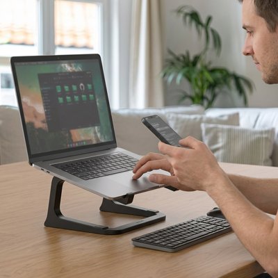 Homme travail sur son ordinateur portable poser sur support pc portable noir
