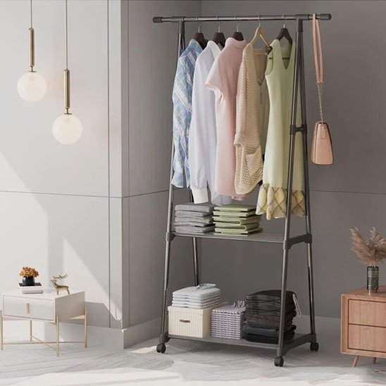 Portant vetement noir dans chambre avec vetments, sac et linges pliés par dessus
