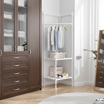 Porte vetement blanc avec des habits accroches dessus a l angle dans chambre a coucher  