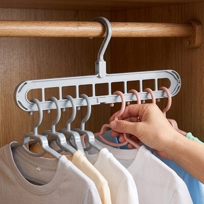 Une main accroche t-shirts sur Cintre gris dans placard
